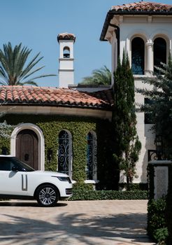 Captivating view of a luxury mansion exterior with ornate details and an elegant SUV parked in front.