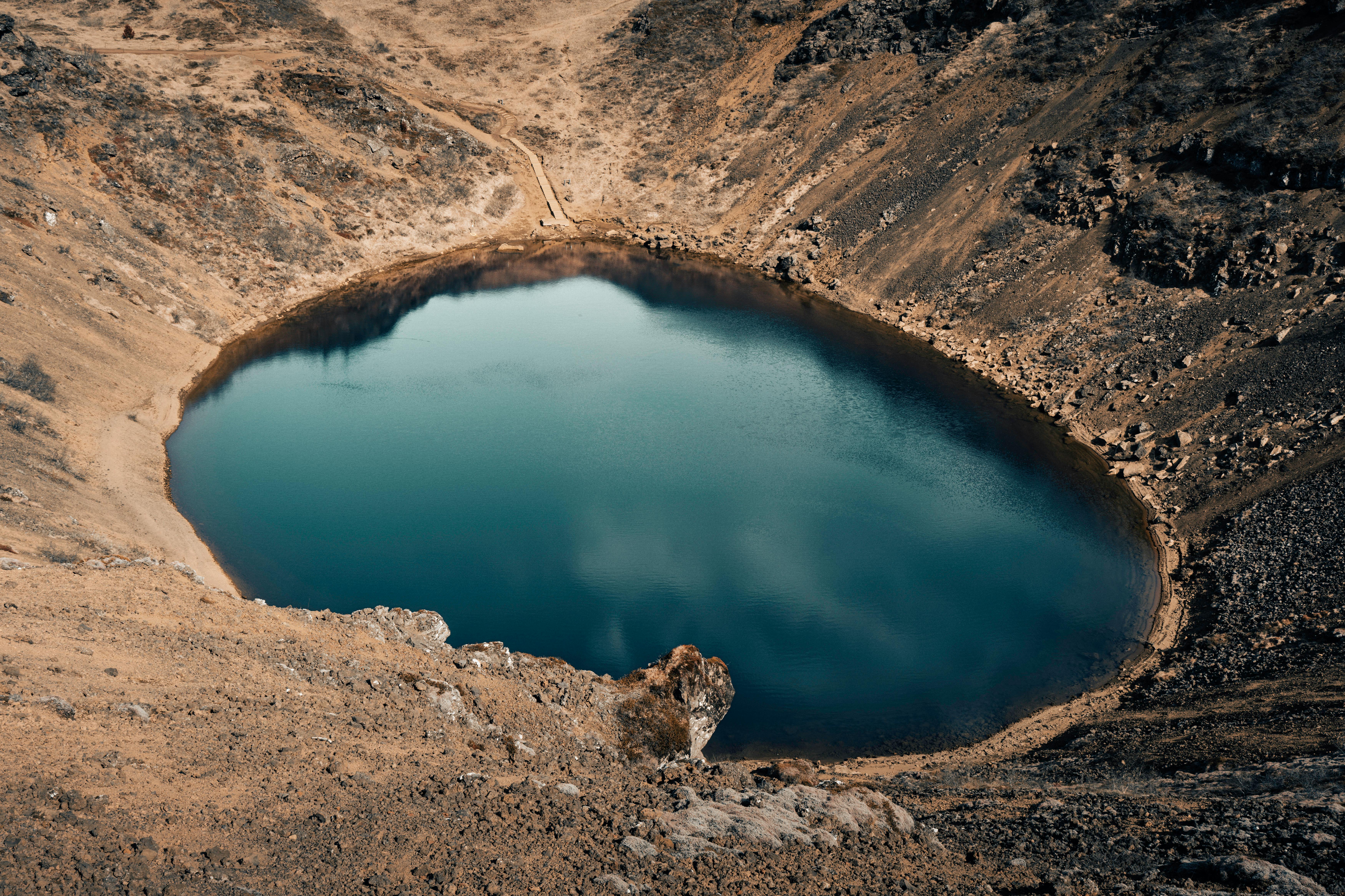 A breathtaking aerial capture of a serene crater lake surrounded by rugged terrain in Iceland.