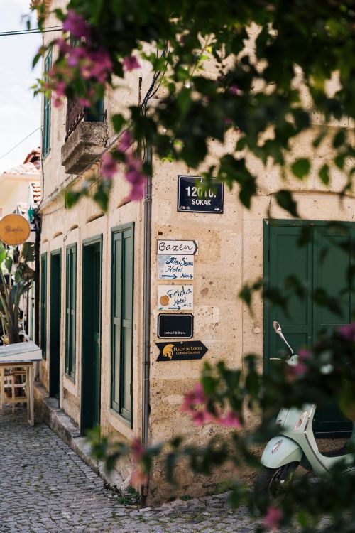 Free Rustic street view of a Mediterranean alley with green shutters and a parked Vespa. Stock Photo