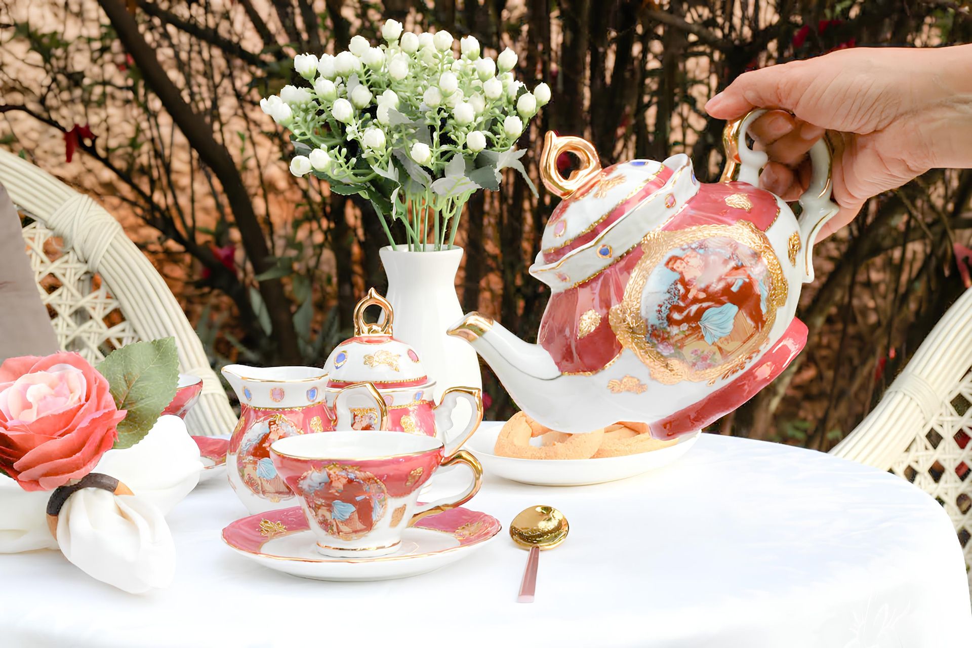 Charming garden tea setting with ornate porcelain tea set, floral decor, and cookies.