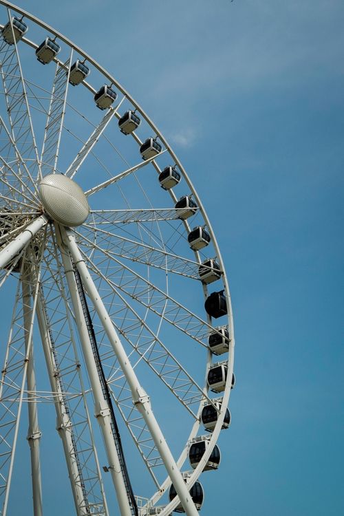 Free Close-up of a giant Ferris wheel with a clear blue sky background, emphasizing its grandeur. Stock Photo