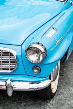 Close-up of a classic blue vintage car's headlight and grille, captured on an overcast day in Bratislava.