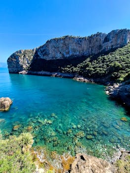 Dramatic view of turquoise waters and rugged cliffs under a clear blue sky, perfect for nature lovers.