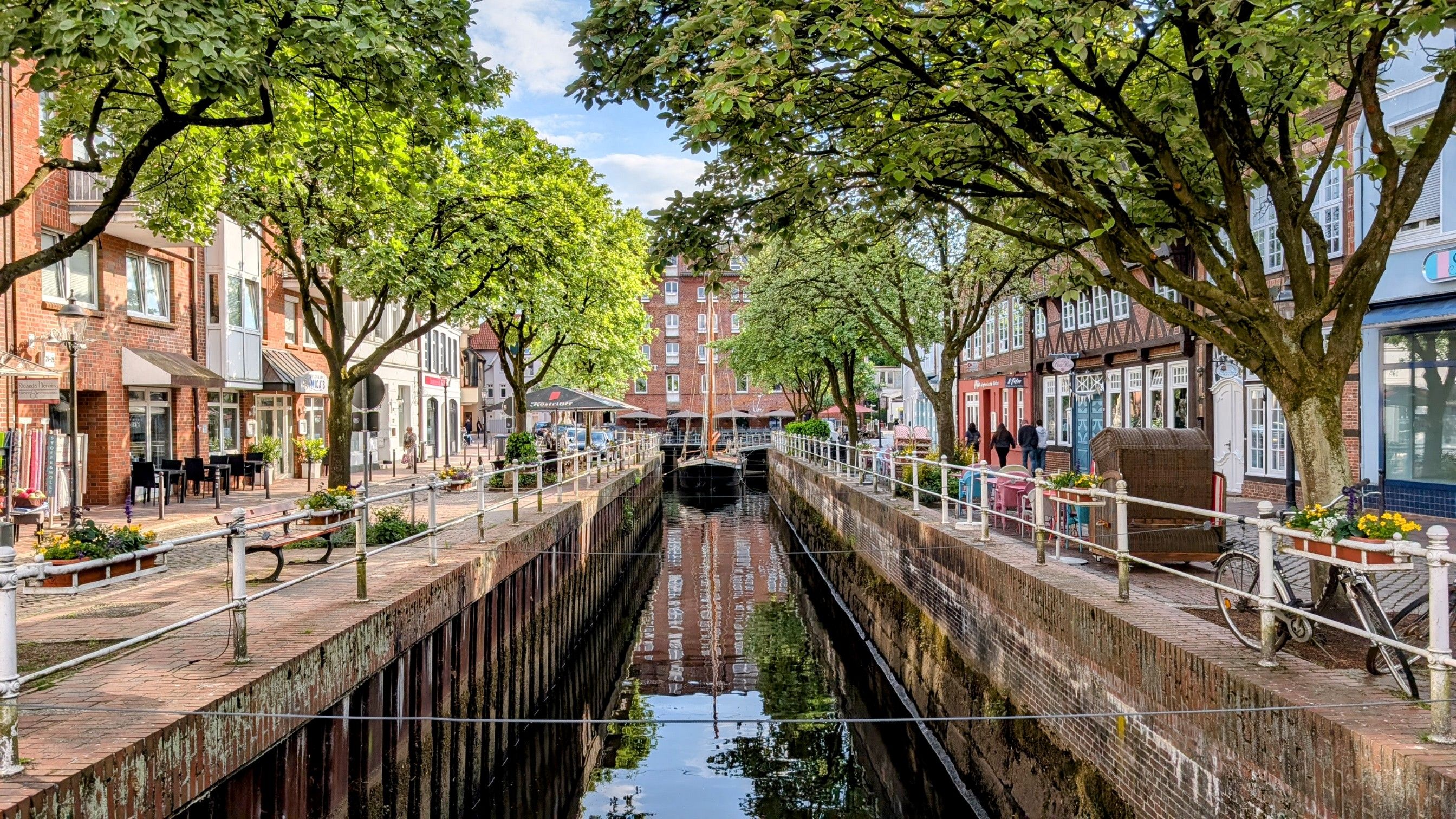 Charming canal scene in a European town with lush greenery.