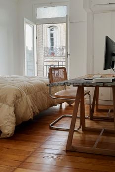 Bright bedroom with a modern workspace and wooden floors in Buenos Aires, Argentina.