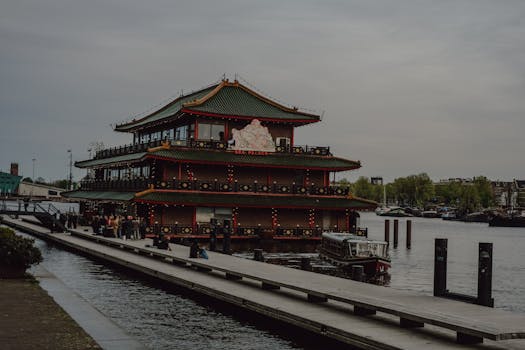 Asian-style floating restaurant on Amsterdam canal during twilight, showcasing unique architecture.