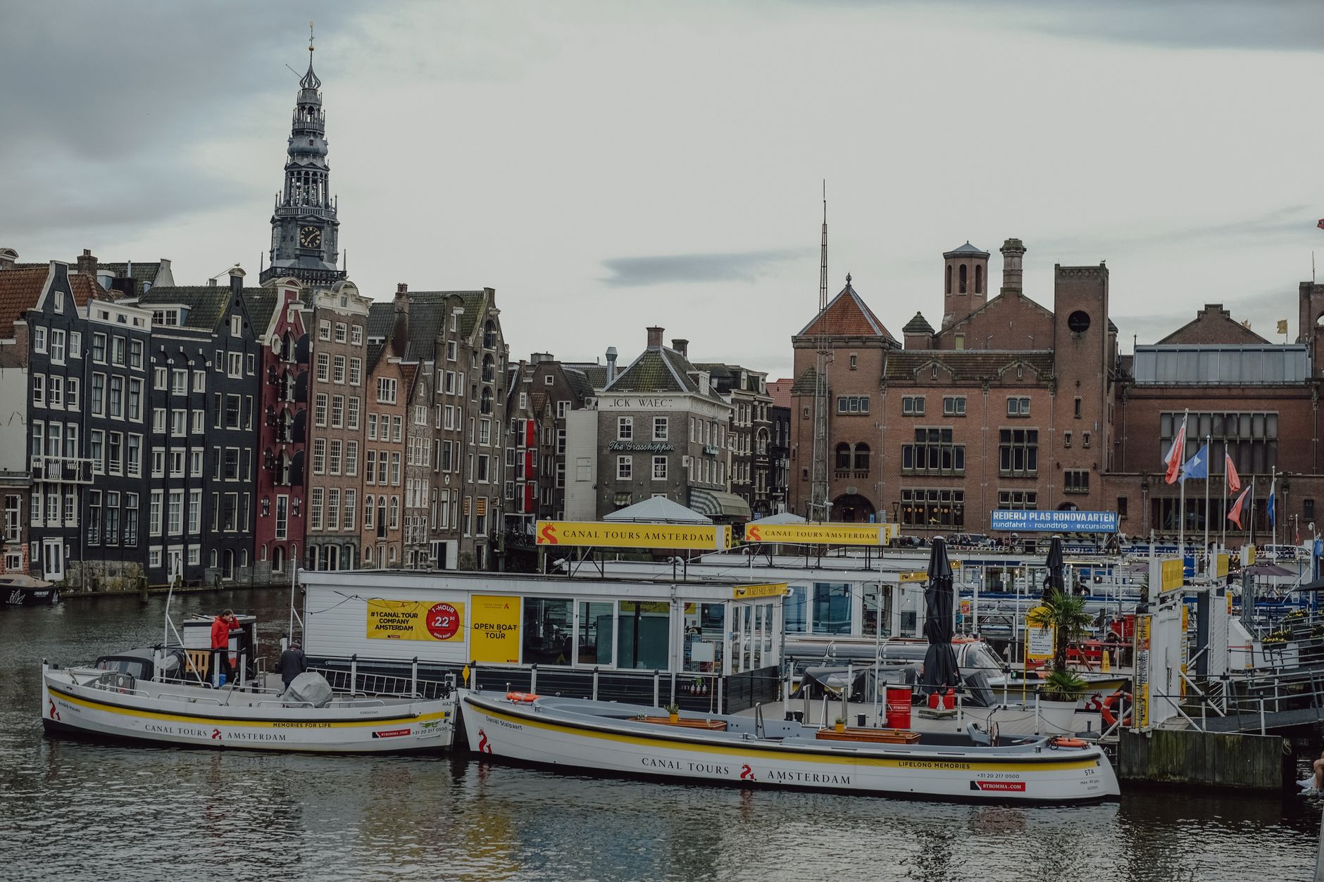 Scenic view of Amsterdam canal boats with historic buildings and Westerkerk tower.