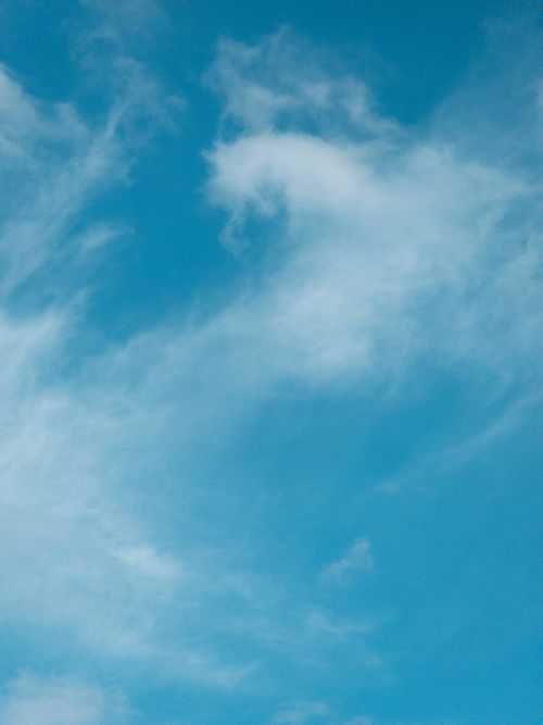 Free A tranquil view of a clear blue sky with soft, wispy white clouds. Stock Photo
