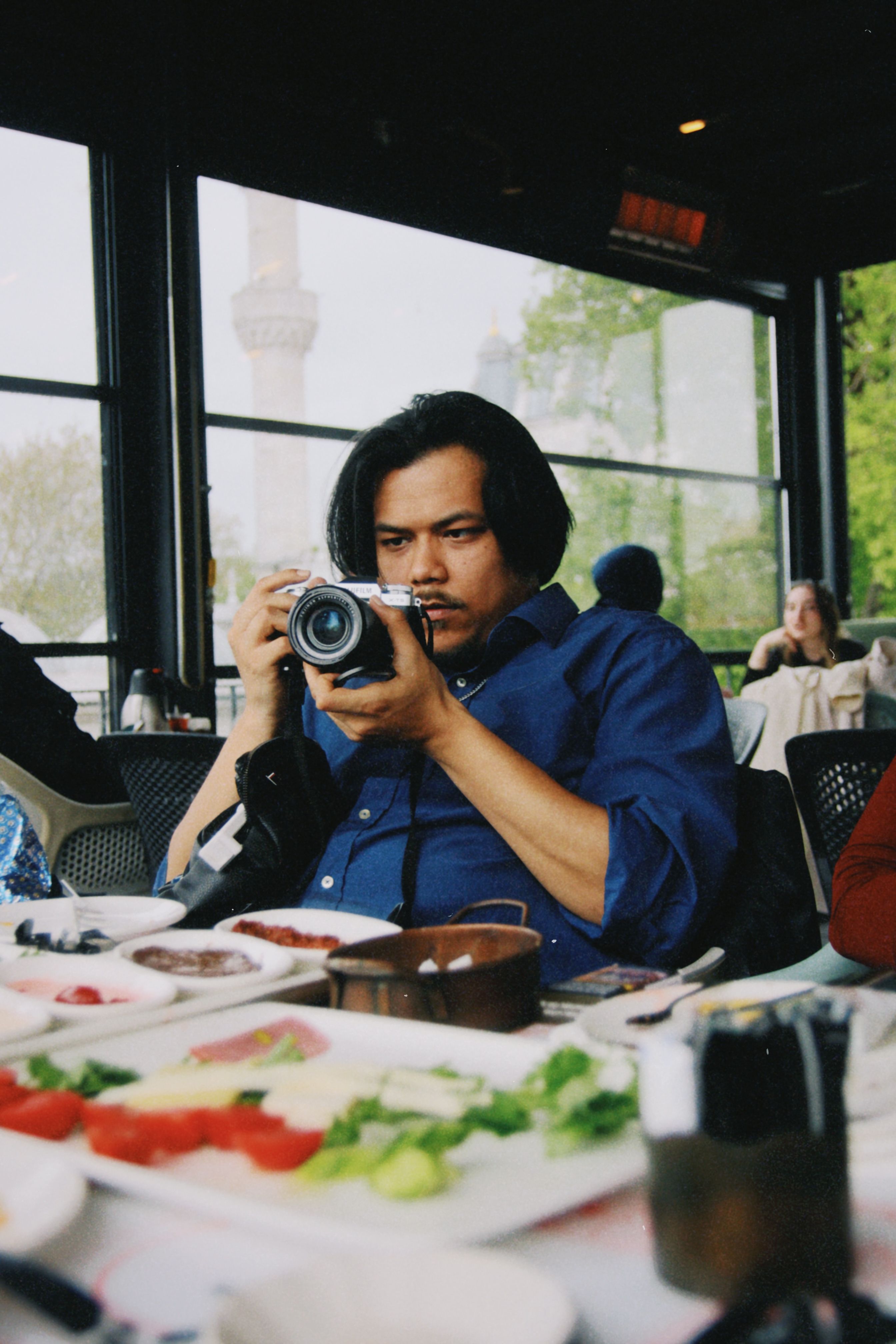 Man focuses camera on dining table setup at restaurant.