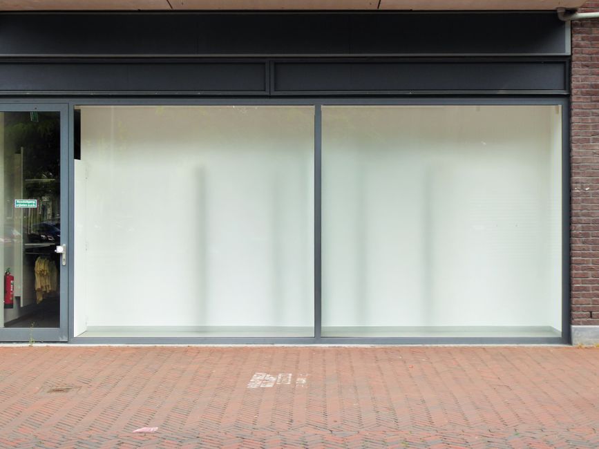 Empty retail storefront space with large windows available for lease