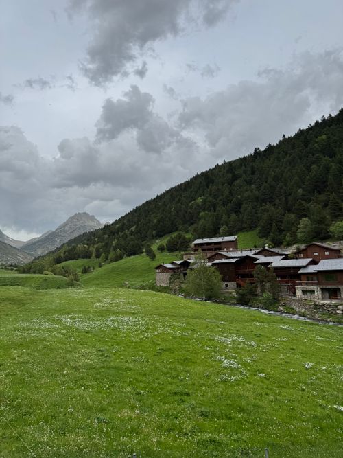 Free Picturesque view of an alpine village with green hills and cloudy sky. Stock Photo