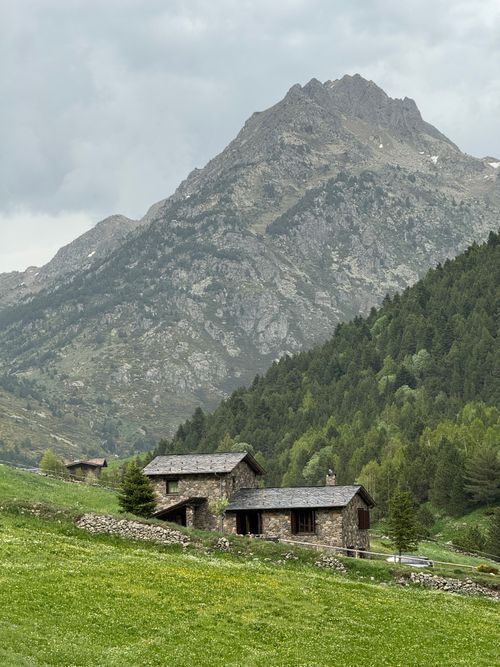 Free Charming stone cabins nestled in lush alpine scenery under a cloudy sky. Stock Photo