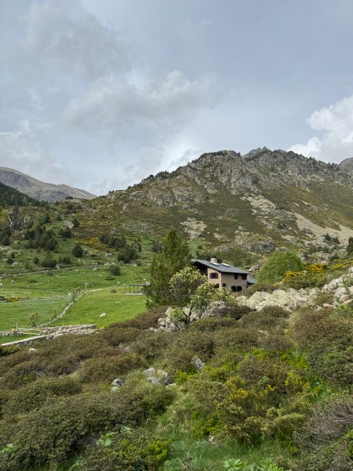 Free Cozy cabin nestled in a lush green mountain valley under a blue sky. Stock Photo