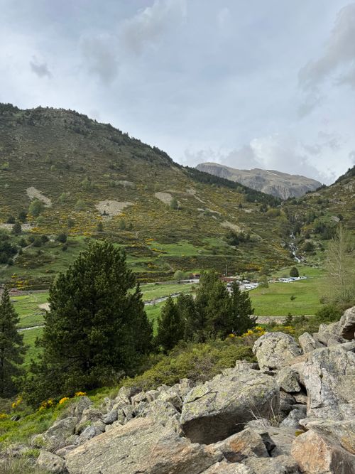 Free A serene mountain valley landscape with greenery and a clear stream flowing through the hills. Stock Photo