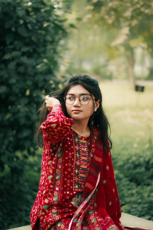 Free Portrait of a young woman in traditional colorful attire, enjoying a serene moment outdoors in Khulna, Bangladesh. Stock Photo