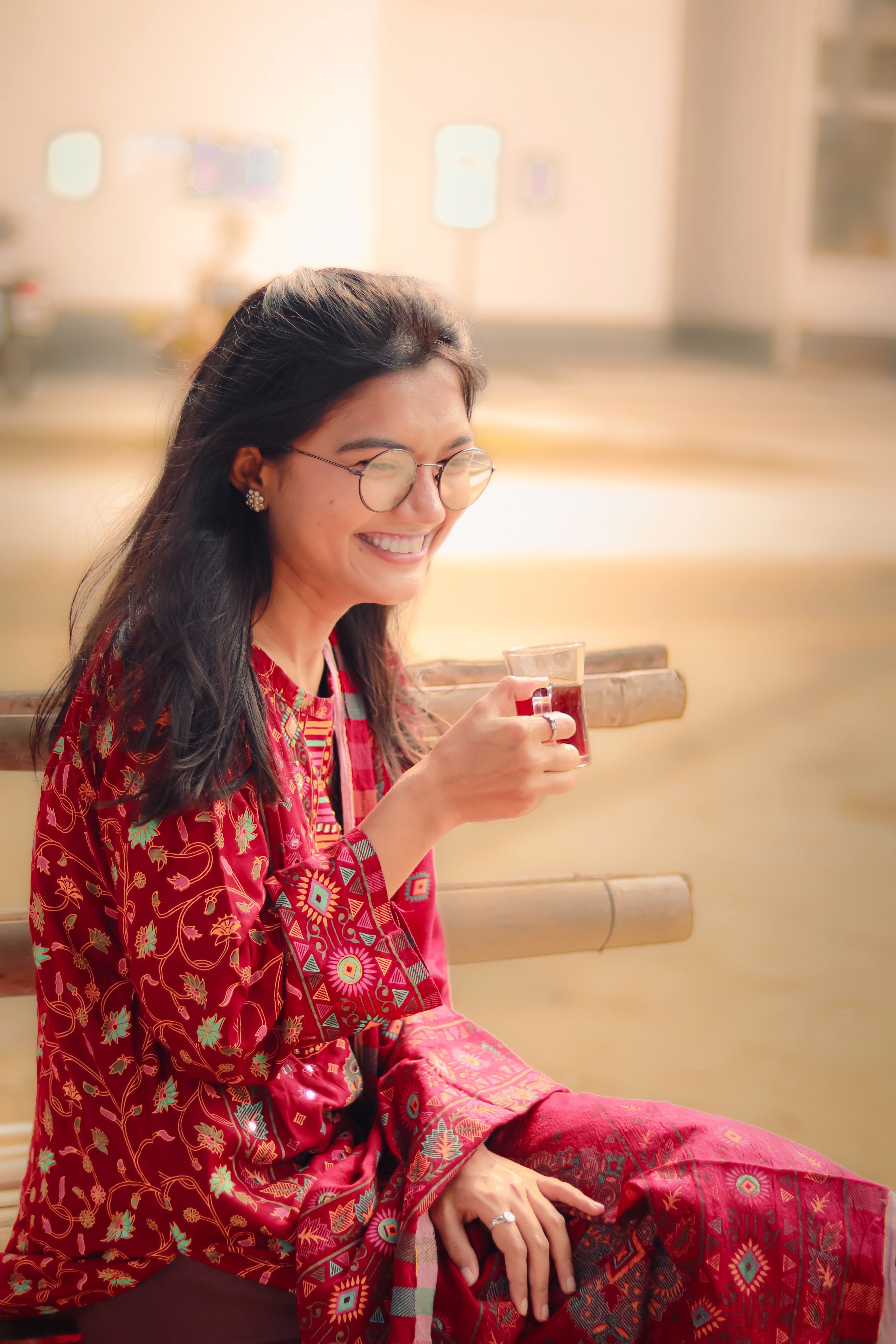 A joyful woman enjoying tea indoors in Khulna, Bangladesh.