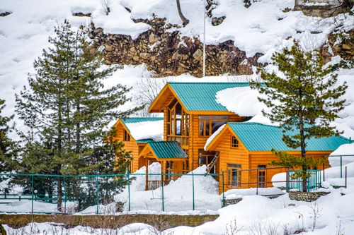 Free Snow-covered wooden chalet in Pahalgam amid picturesque winter scenery. Stock Photo