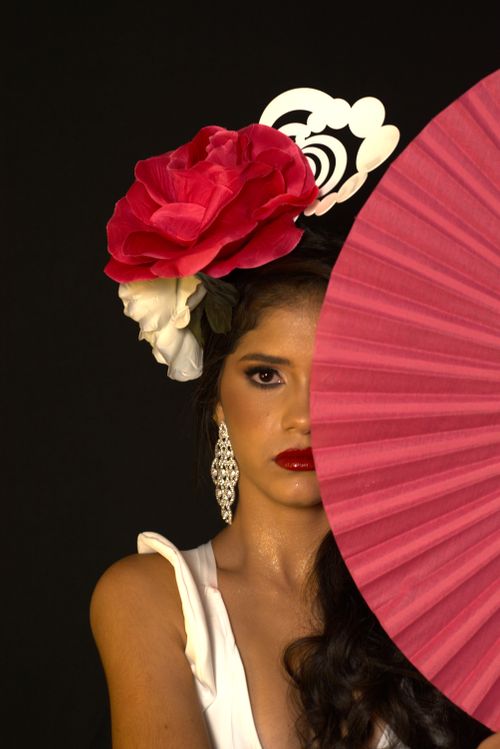 Free Stylish portrait of woman wearing a red rose headpiece and white dress against black background. Stock Photo