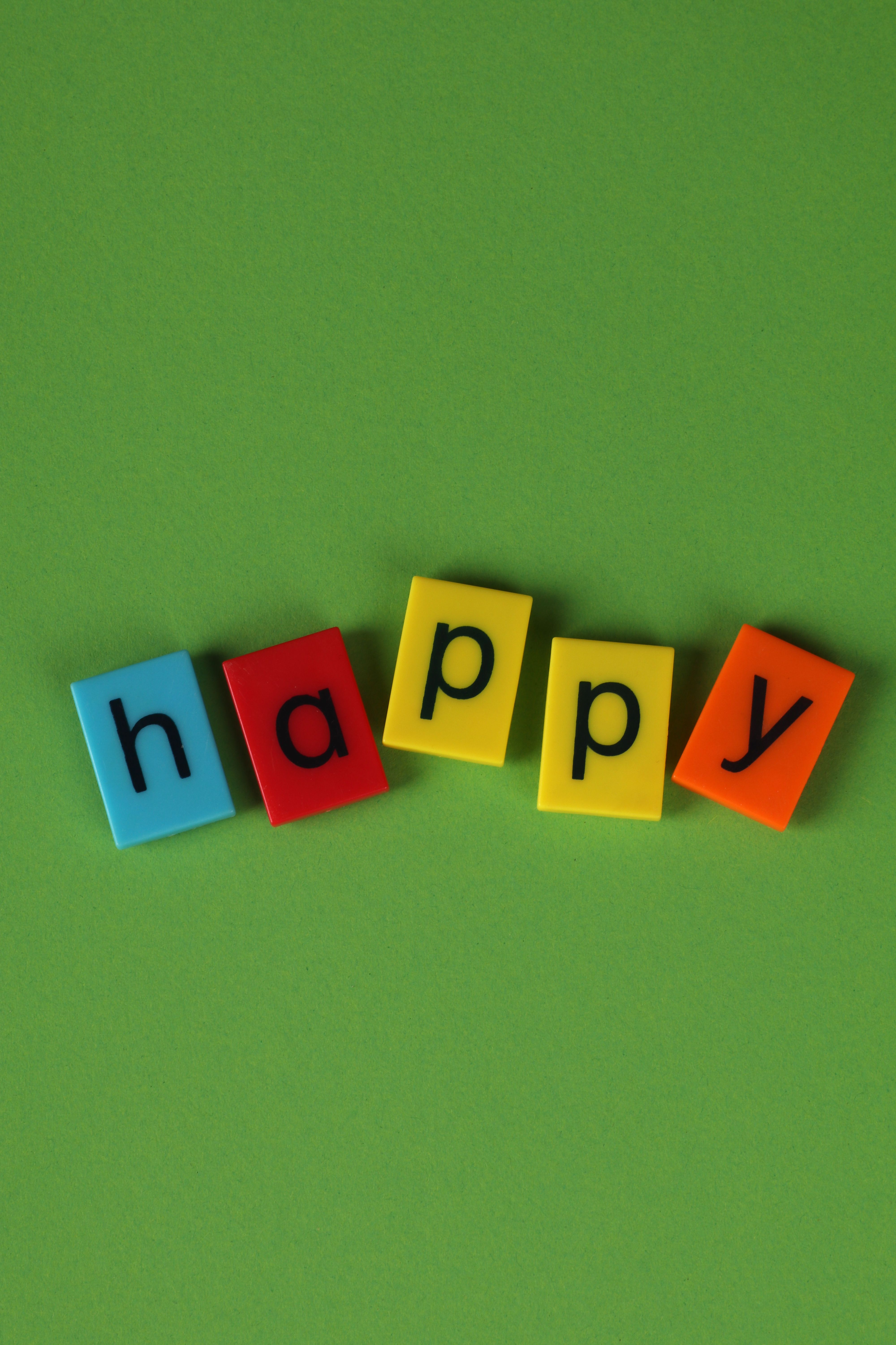 Cheerful and vibrant blocks spelling 'happy' on a green backdrop, perfect for positive messages.