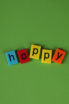 Cheerful and vibrant blocks spelling 'happy' on a green backdrop, perfect for positive messages.