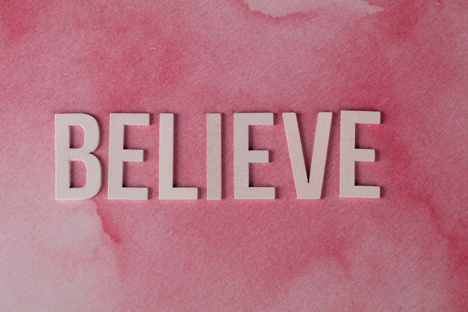 Inspirational word 'Believe' crafted on a textured pink watercolor background. Ideal for motivation.