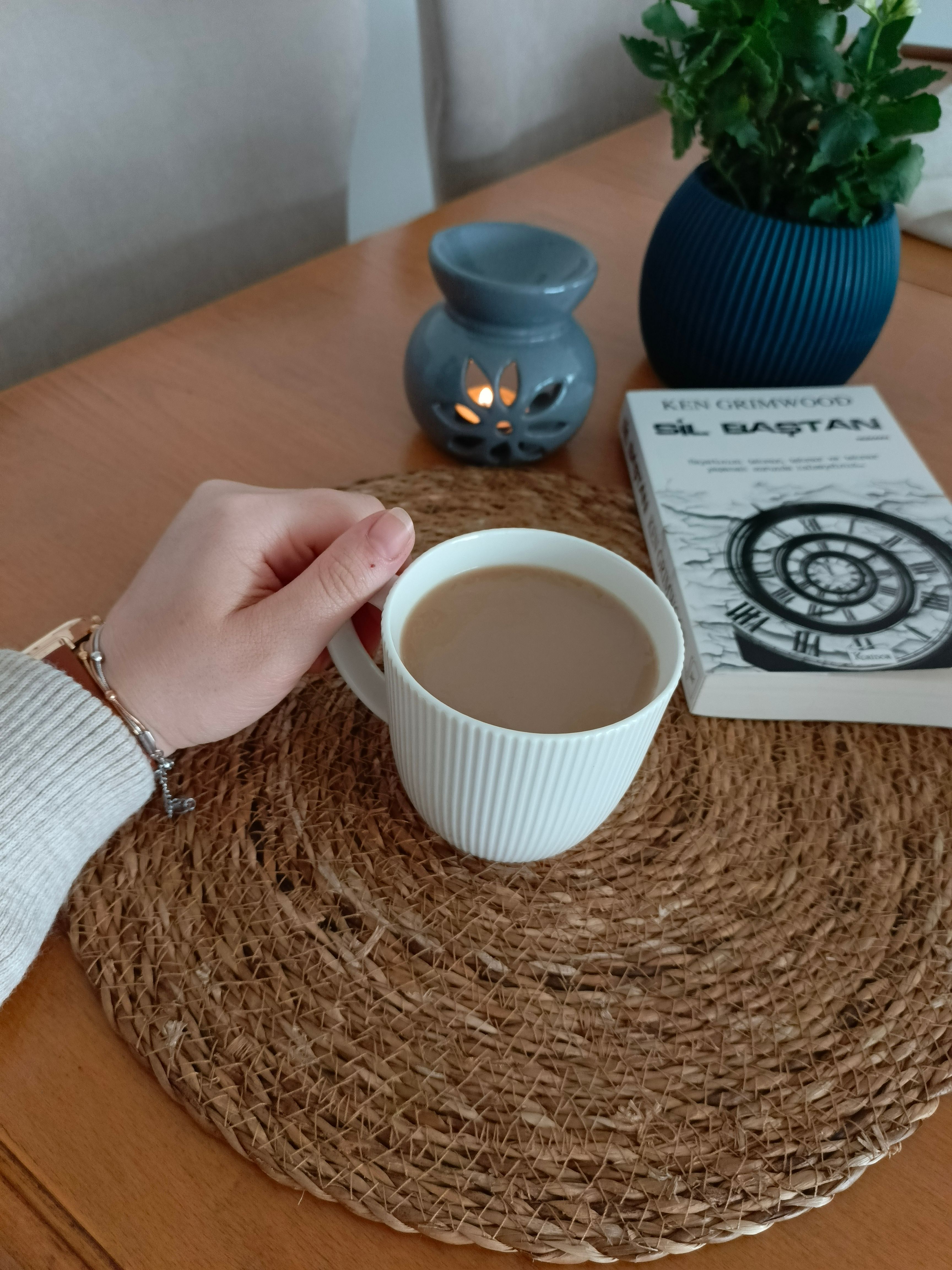 Relaxing morning with coffee, book, and candle on a wooden table. Perfect for a peaceful start to the day.