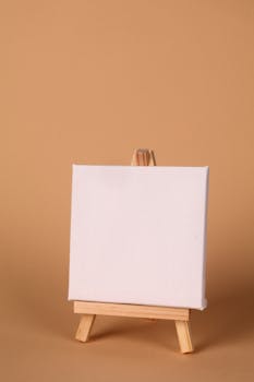 Blank white canvas on a small wooden easel against a brown background.