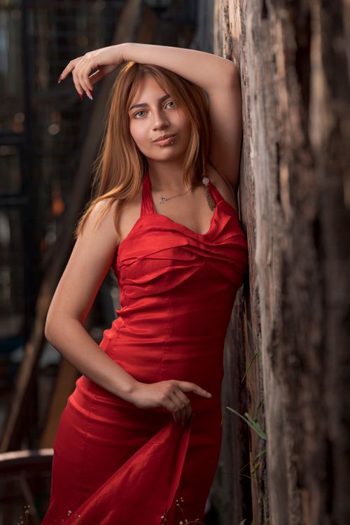 Free Elegant portrait of a woman in a red dress leaning against a wooden wall in Tlaxcala. Stock Photo