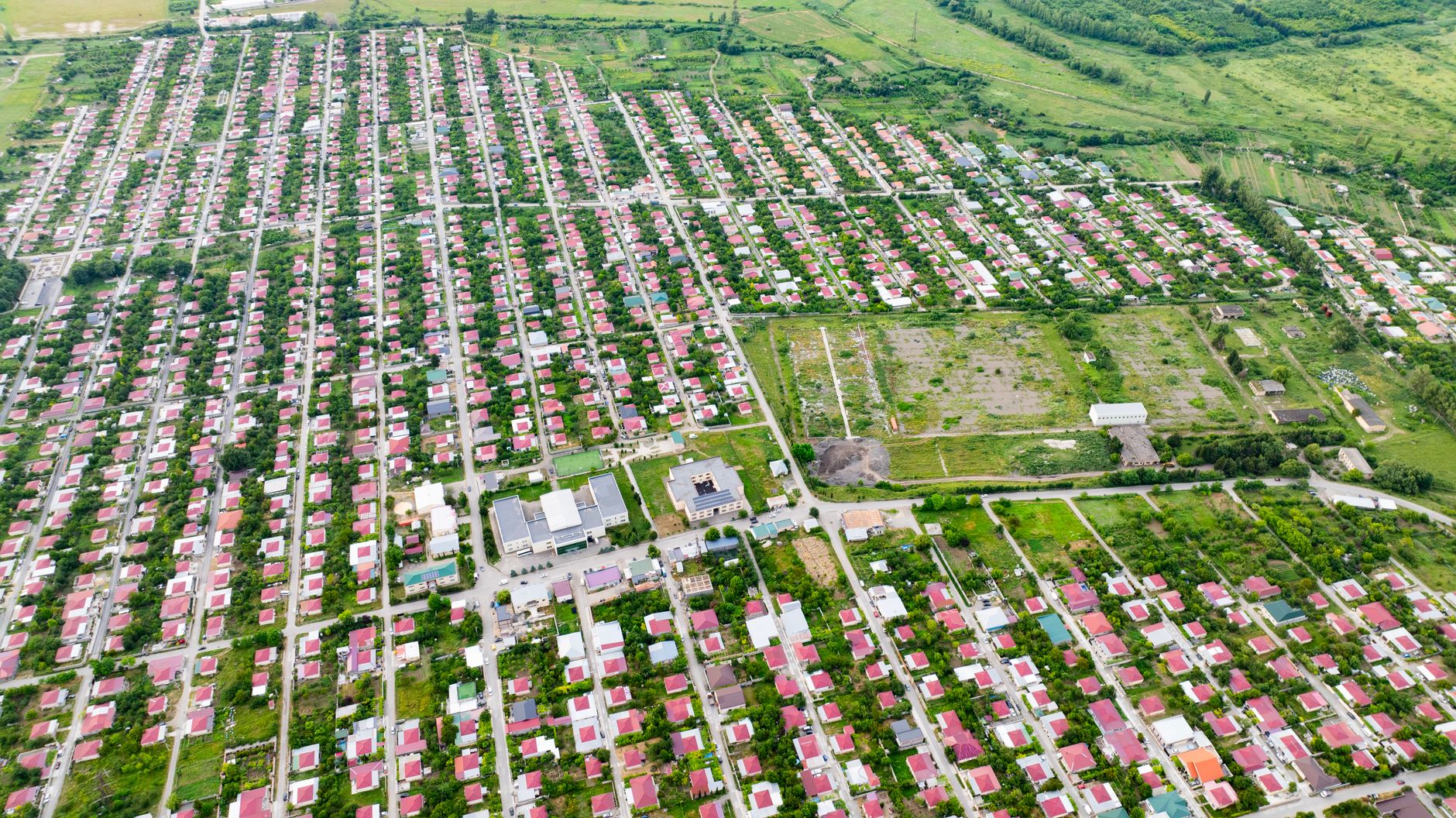 Expansive aerial view of Tserovani village with rows of red-roofed houses and greenery.