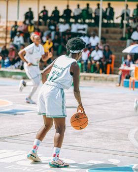 Outdoor basketball match with players in action on a sunny day.