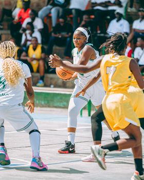 Action-packed moment in a women's outdoor basketball game with focus on player dribbling the ball.