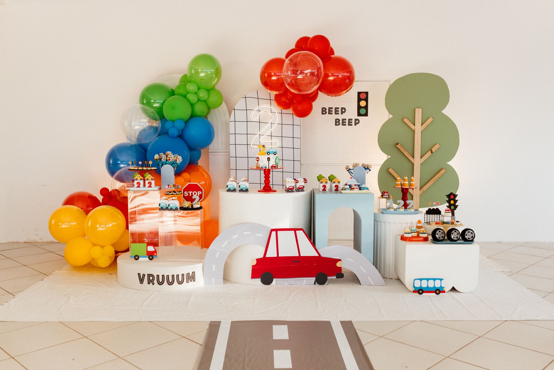 Vibrant transportation-themed children's party setup with balloons and road decorations.