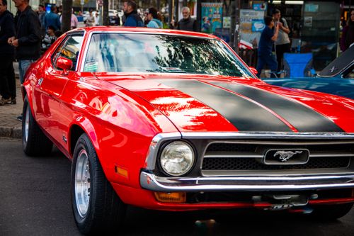 Free Stunning red classic Ford Mustang with black stripes parked on a busy city street. Stock Photo
