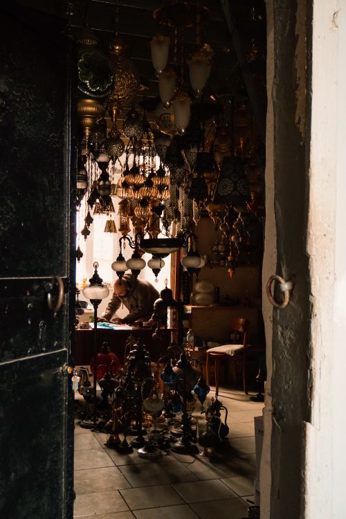 Free A dimly lit antique store filled with vintage lamps and a person examining artifacts. Stock Photo