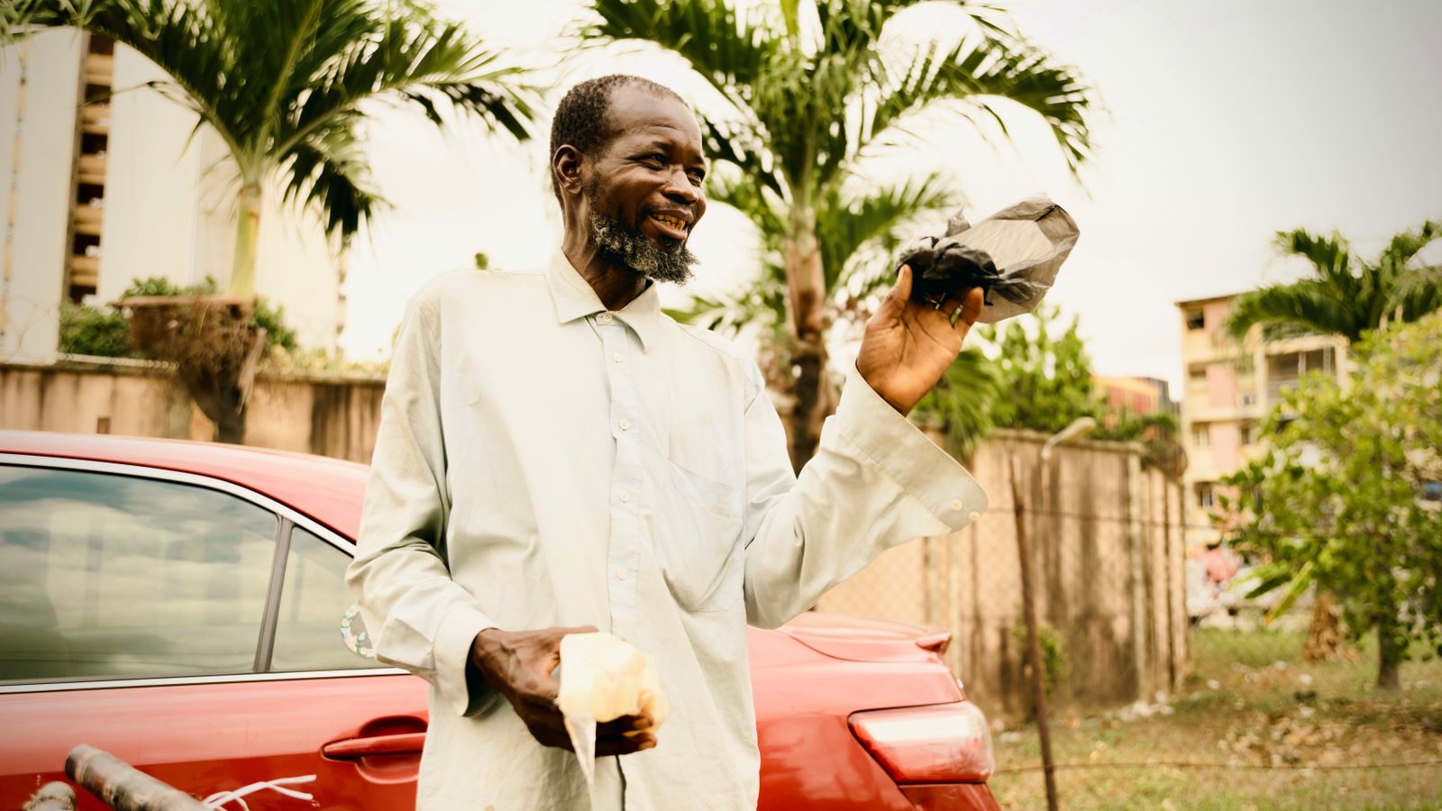 Smiling man holding package outdoors in urban setting, Côte d'Ivoire