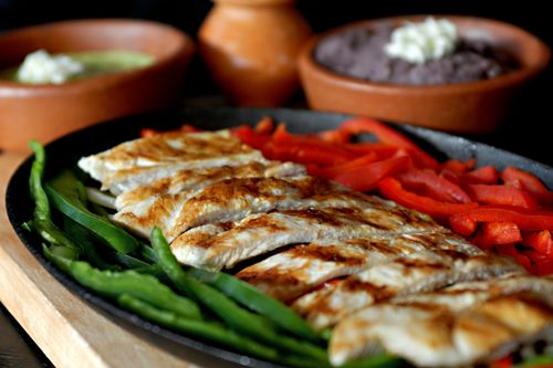 Free Tasty chicken fajitas served with colorful bell peppers and traditional Mexican sides. Stock Photo
