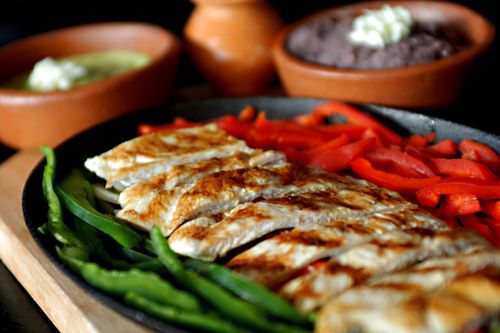 Free Delicious grilled chicken fajitas with bell peppers, served with traditional Mexican sauces. Stock Photo