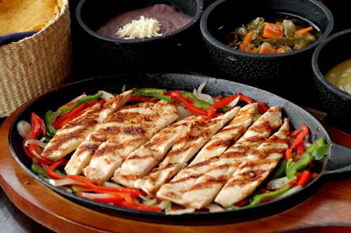 Free Delicious grilled chicken fajitas served with colorful vegetables and traditional Mexican sides. Stock Photo