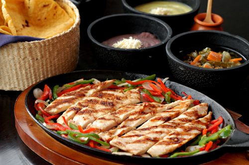 Free Sizzling grilled chicken fajitas with peppers, tortillas, and beans served in Mexico City. Stock Photo