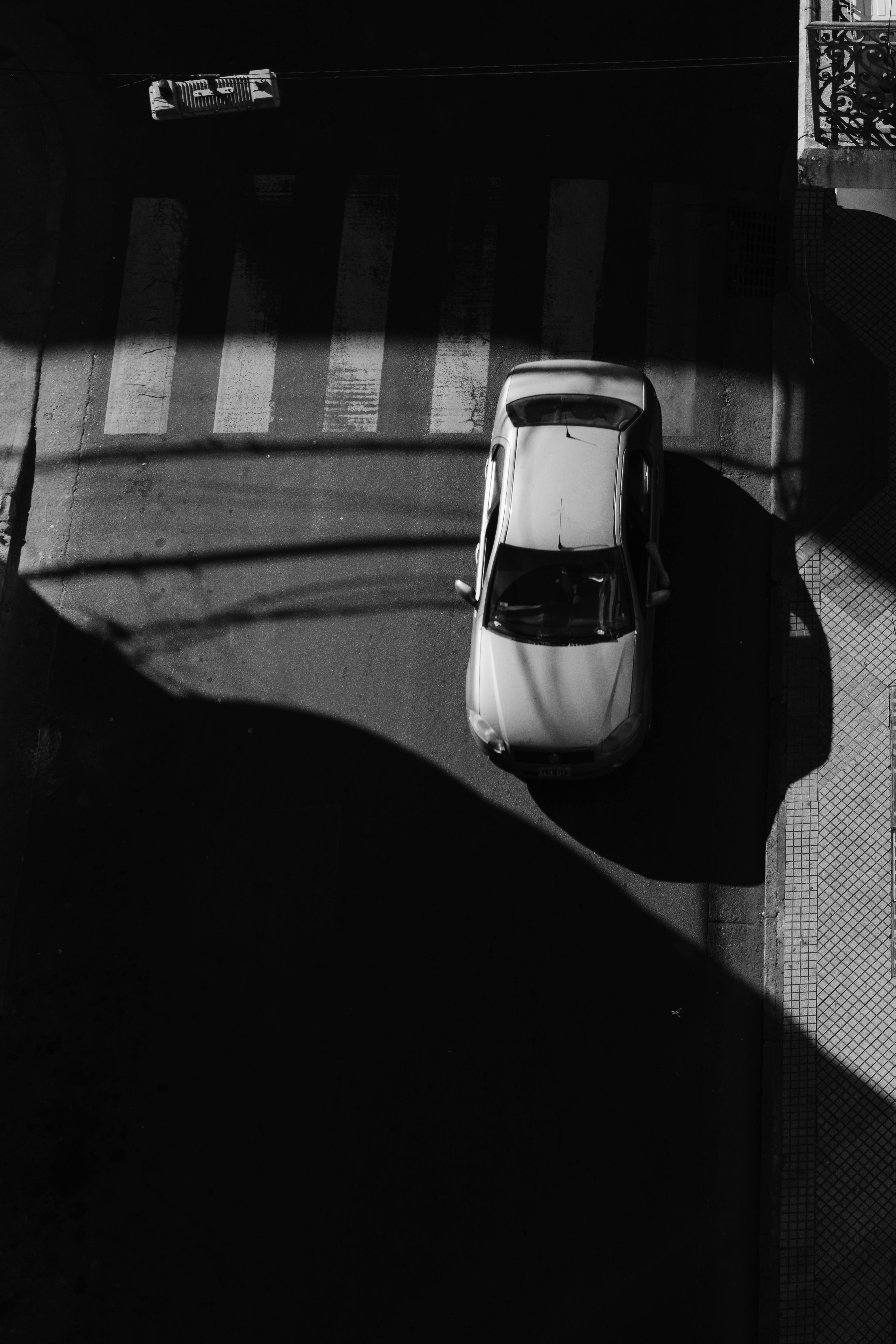 A striking black and white street scene in Rosario, Argentina, featuring dramatic shadows and a parked car.