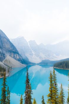 Crystal-clear turquoise waters of Moraine Lake surrounded by majestic mountains and pine trees in Banff National Park.