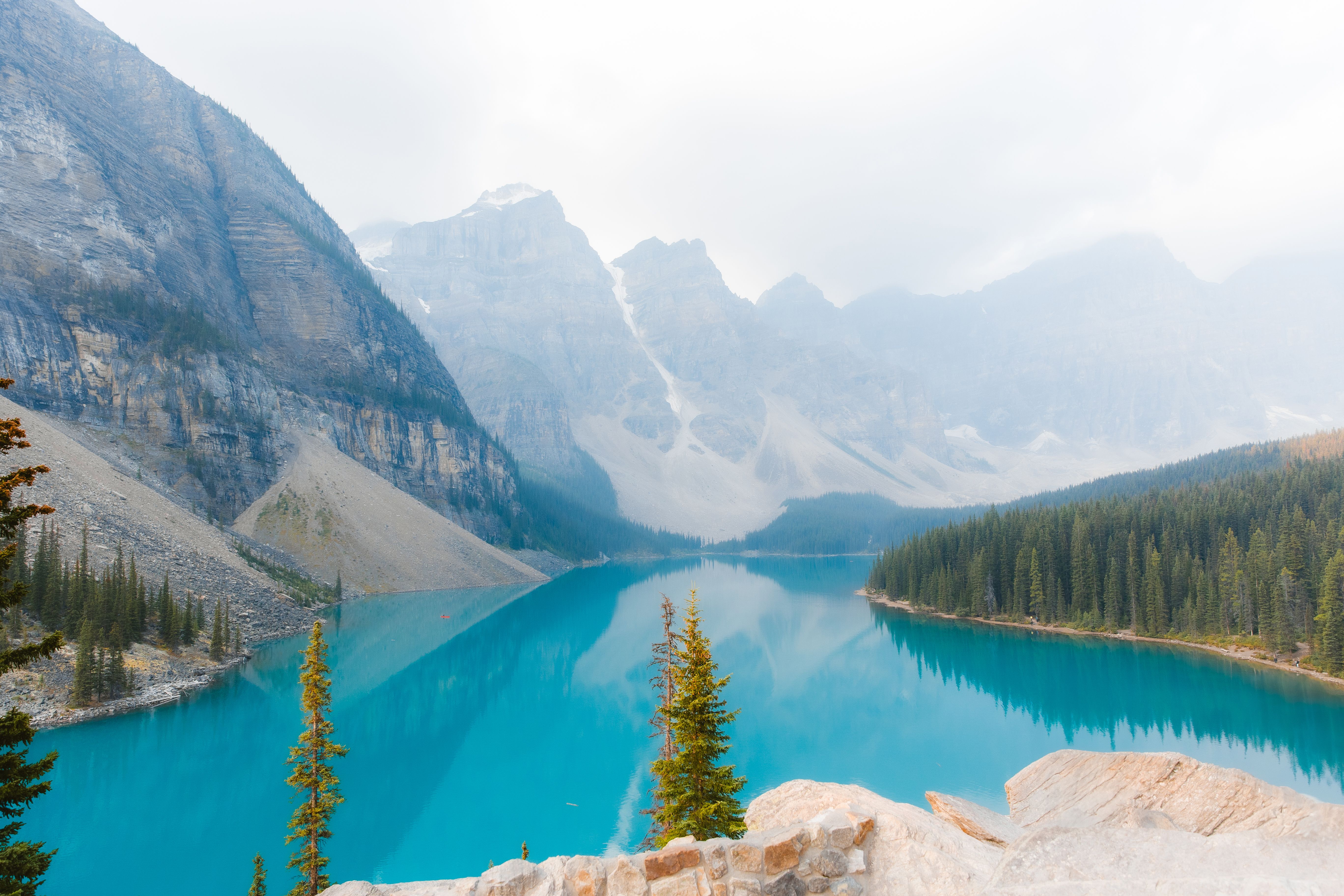 Free Turquoise Moraine Lake in Banff with mountain and pine trees under a clear blue sky. Stock Photo