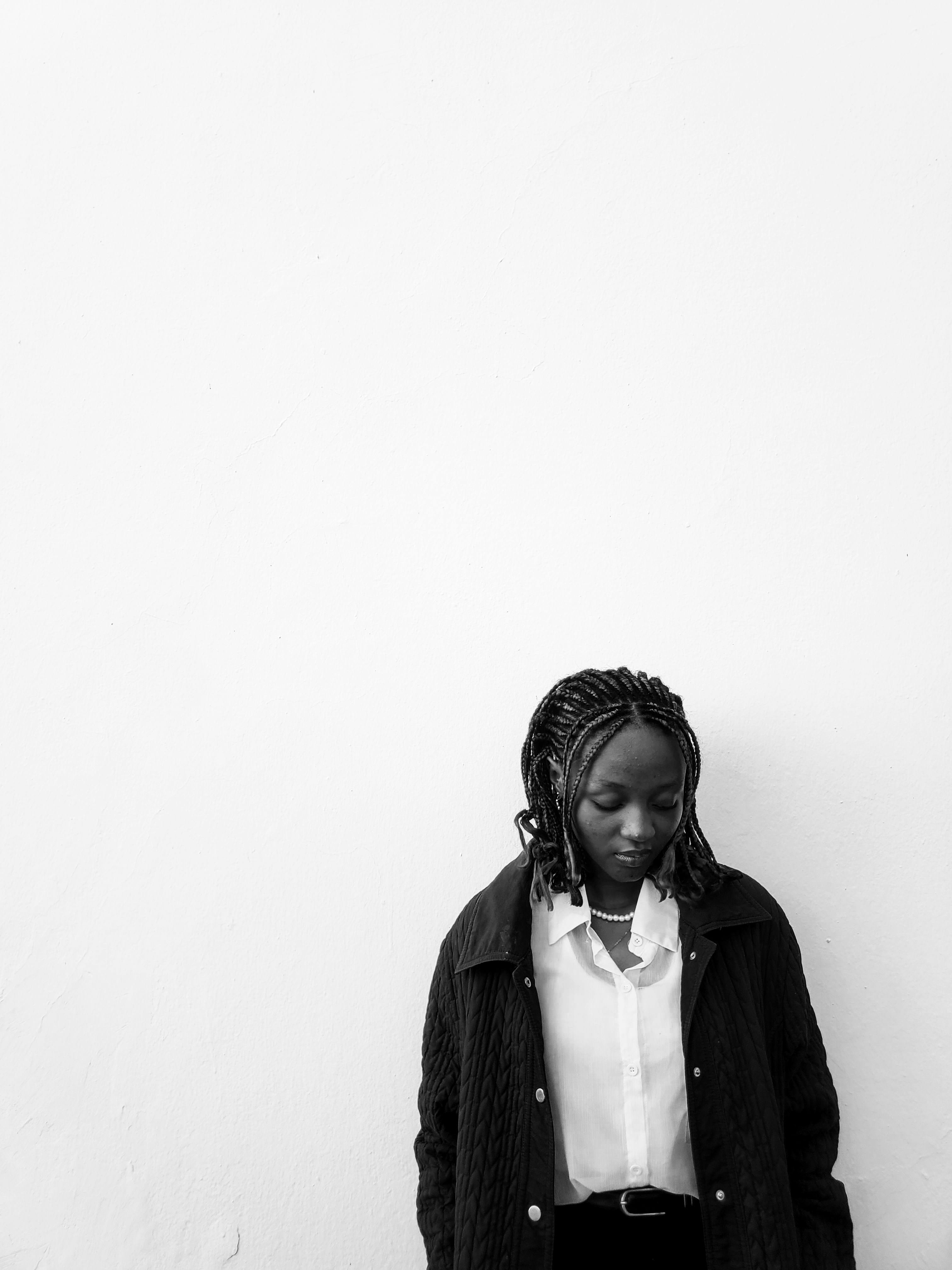 Monochrome portrait of a woman against a white wall, exuding calm and elegance.
