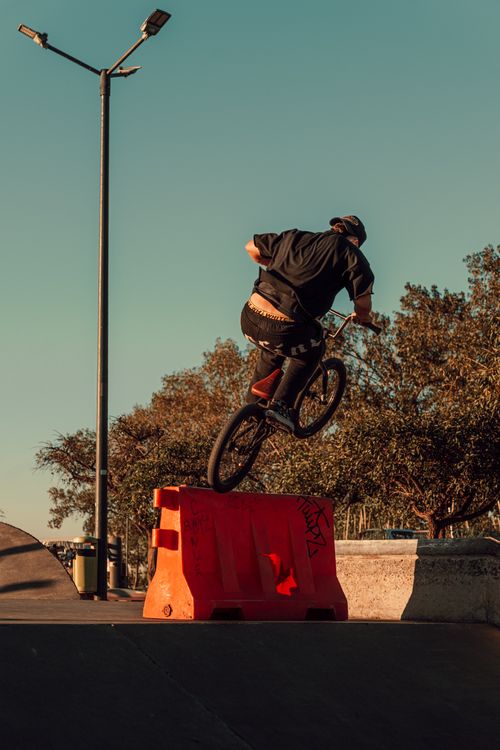 Free A BMX rider executing a high jump at an outdoor skate park under clear skies. Stock Photo
