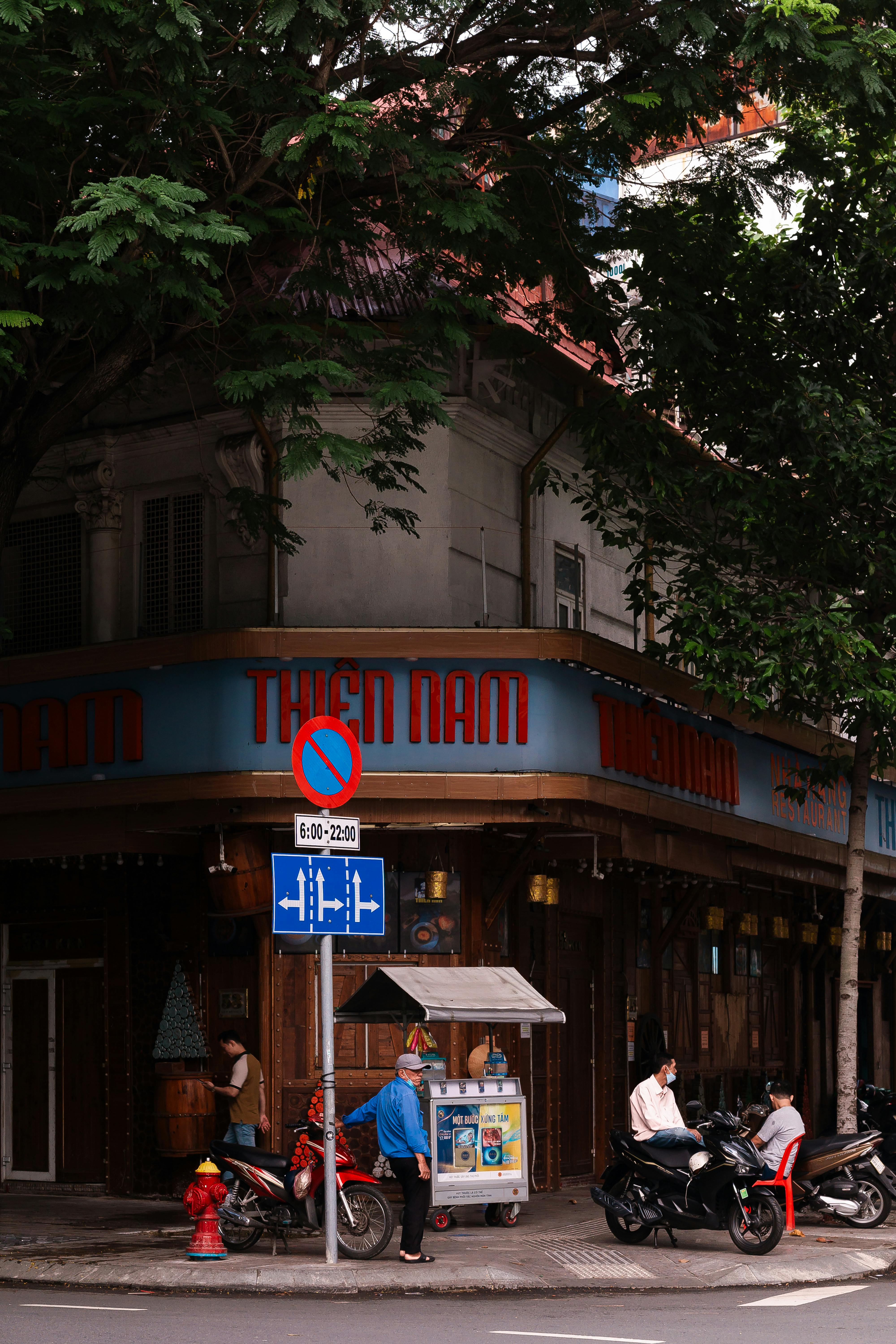 Street scene in Ho Chi Minh City with people and motorcycles by a local store.