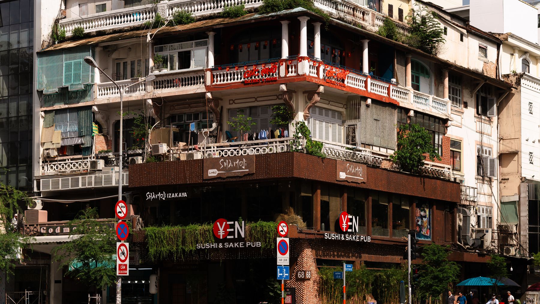 A multi-story historic building featuring a modern sushi and sake pub on the ground floor and lush greenery.