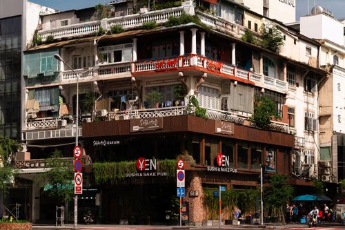 Free A multi-story historic building featuring a modern sushi and sake pub on the ground floor and lush greenery. Stock Photo