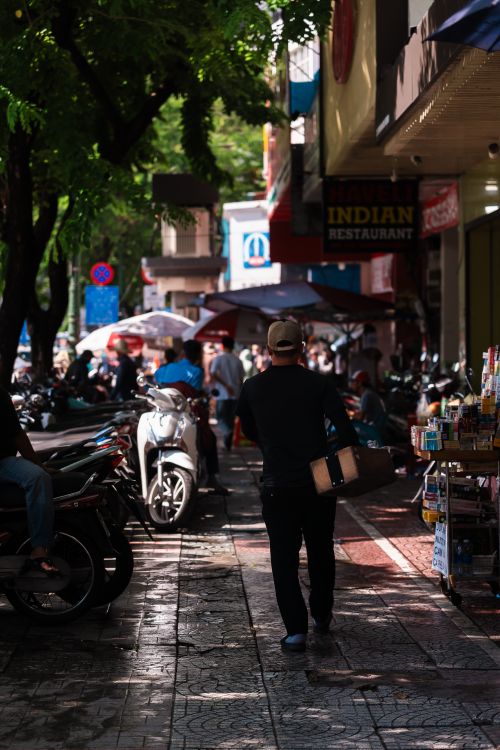 Free Vibrant street scene with pedestrians near an Indian restaurant, motorbikes, and vendors. Stock Photo