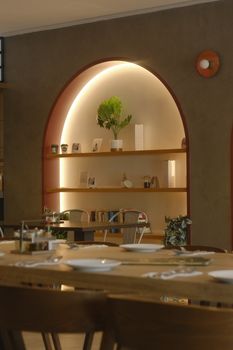 Warmly lit restaurant interior with arched shelves and dining tables, creating an inviting atmosphere.