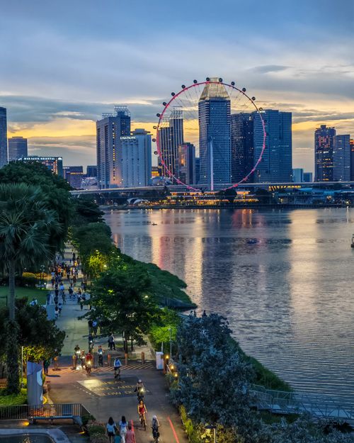 Free Vibrant view of Singapore's skyline and Ferris wheel at twilight, reflecting on Marina Bay. Stock Photo